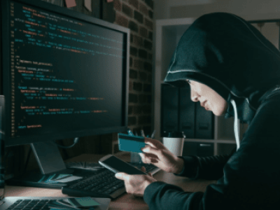 hacker looking at phone by a computer screen, Cybersecurity, Ransomware Protection