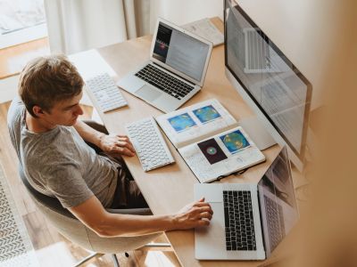Man sitting at table with two laptops and monitor, Cyberscore, cybersecurity companies Chicago
